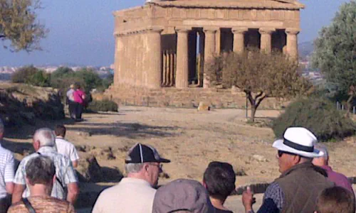Visiteurs découvrant les temples grecs d'Agrigente avec un guide